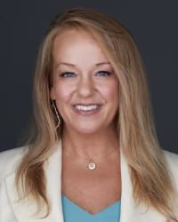 A woman wearing a white jacket and a blue shirt is smiling for the camera.